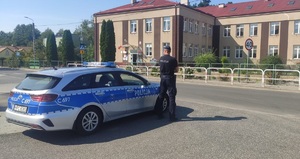 policjant przy radiowozie stojący przy szkole