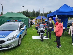 stoisko policyjne przy którym stoja mieszkaćy, na zdjęciu motocykl, radiowód