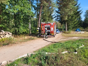 policjanci stoja przed strażackim wozem i zabezpieczają droge