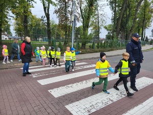 policjant przeprowadza dzieci przez jezdnie na przejsciu dla pieszych