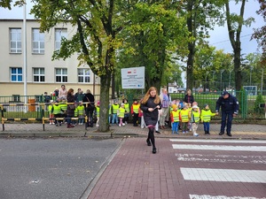 policjant z dziecmi stoja przez przejściem dla pieszych