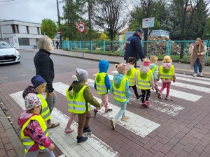 policjant z dziecmi przechodzi przez jezdnie