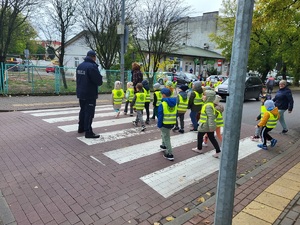 policjant stoi na drodze, dzieci przechodzą przez pasy