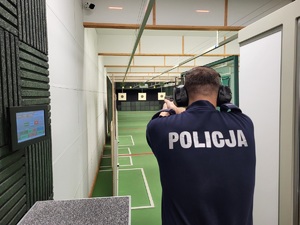 policjant na stanowisku strzeleckim oddaje strzał do tarczy