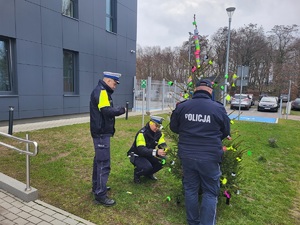 policjanci zawieszaja opaski i zawieszki odblaskowe na choince