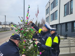 policjanci zawieszaja opaski i zawieszki odblaskowe na choince