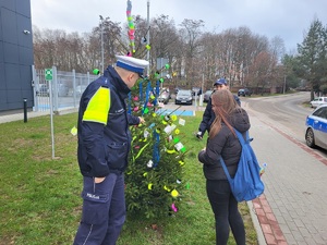 policjanci zawieszaja opaski i zawieszki odblaskowe na choince