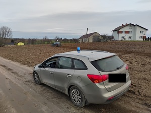 policyjny radiowóz nieoznakowany przy drodze, na polu stoi zatrzymay opel