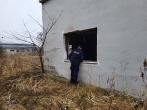 policjant zaglądający do wnętrza bydynku przez okno