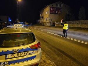 policjant stoi na jezdni i daje znak latarka do zatrzymania