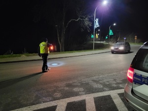 policjant na drodze daje znak latarka do zatzrymania sie pojazdu