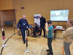 policjant stoi przy dzieciach, którzy pokonują slalom