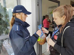 policjantka wrecza wolontariuszom odblaski i ulotki