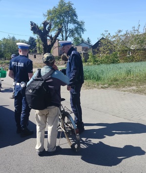 dwóch policjantów stoi na drodze przy kontrolowanym rowerzyście