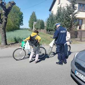 policjant stoi przy dwóch rowerzystach i ich kontroluje