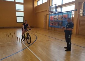 policjant stoi przy chłopcu, który na rowerze pokonuje tor przeszków