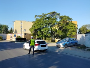 policjant podchodzi do zatrzymanego pojazdu na drodze