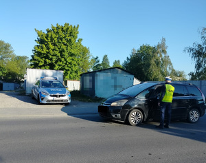 policjant podchodzi do zatrzymanego pojazdu na drodze
