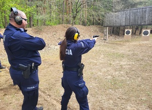 kobieta policjantka oddaje strzały, obok stoi zabezpieczający policjant