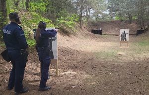 policjantka oddaje strzał do tarczy, obok stoi policjant zabezpieczający