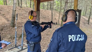 policjant na stanowisku strzeleckim trzyma broń, oboj stoi policjant zabezpieczający