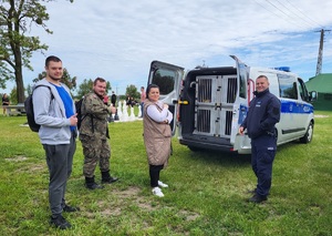 policjant stoi przy radiowozie i rozmawia z zebranymi osobami