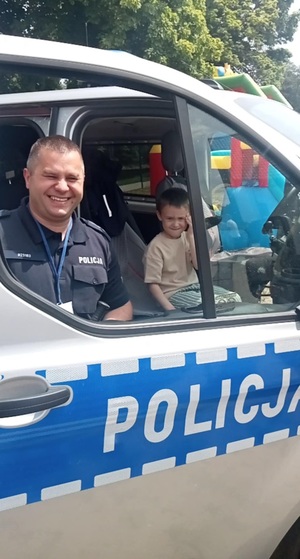 policjant i jedno dziecko stoja w radiowozie