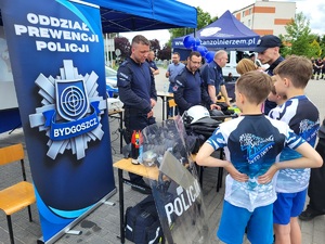 uczestnicy wydarzenia stoja przy policyjnym stanowisku i rozmawiają zpolicjantami