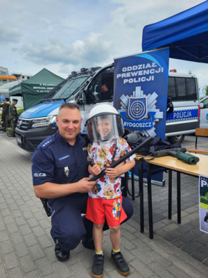 policjant z małym chłopcem, który ma na sobie założony policyjny sprzet