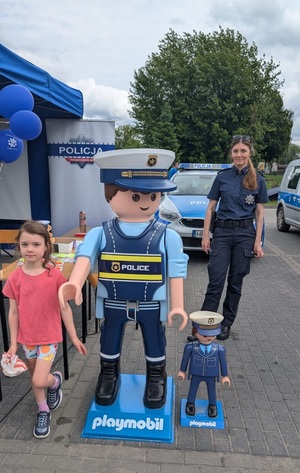policjantka oraz mała dziewczynka stoja przy maskotkach policyjnych