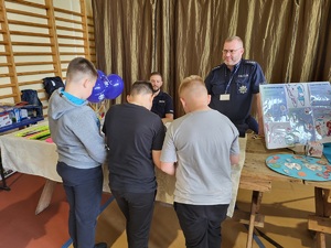 trzech chłopców stoi przy policyjnym stanowisku
