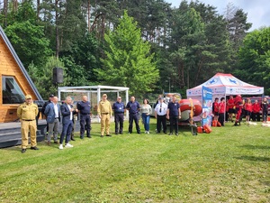 przedstawiciele słuzb stoja na łące podczas rozpoczecia pikniku