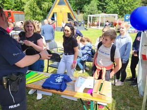 policjant przy stoisku pokazuje tubę prezentującą odblaski