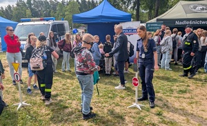 policjantka stoi przy znaku drogowym, dziecko ma na głowie załozone alkogoogle
