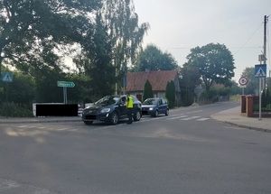 policjant stoi przy samochodzie na drodze i podaje urządzenie do badania stanu trzexwości kierowcy