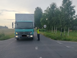 policjant stoi przy samochodzie na drodze i podaje urządzenie do badania stanu trzexwości kierowcy