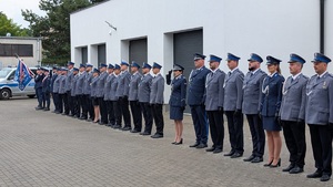 zdjecie stojących policjantów w szeregu, na końcu stoi radiowóz