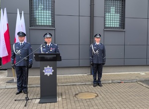 na mównicy stoi z-ca Komendanta Wojewódzkiego, po obu stronach stoja policjanci z tyłu stoi stojak z flagami rzeczypospolitej Polskiej