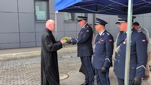 Ksiądz wręcza Komendantowi Policji zapakowana paczkę