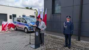 na mównicy stoi Prokurator Rejonowy w Rypinie po obu stronach stoja policjanci z tyłu stoi stojak z flagami rzeczypospolitej Polskiej