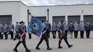 trzech policjantów niosacych sztandar wyprowadza sztandar z placu