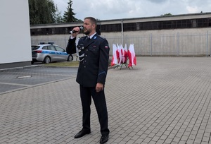 policjant stoi na placu , trzyma w ręku mikrofon i spiewa