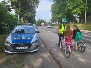 policjant stoi przed dwiema rowerzystkami i je kontroluje