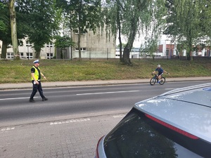 policjant na drodze daje znak rowerzyście do zatrzymania sie