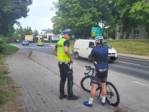 policjant stoi przy rowerzyście i prowadzi kontrolę