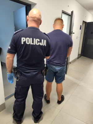 policjant prowadzi zatrzymanego do celi