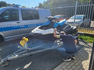 policjant ogląda zabezpieczony skuter, który stoi na przyczepce