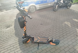 zdjęcie hulajnogi elektrycznej, w tle radiowóz oraz motorower