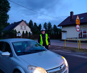 policjant stoi przy pojeździe na drodze i sprawdza stan trzexwości kierowcy