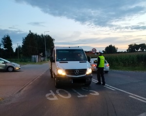 policjant stoi przy zatrzymanym pojexdzie i sprawdza stan trzexwości kierowcy